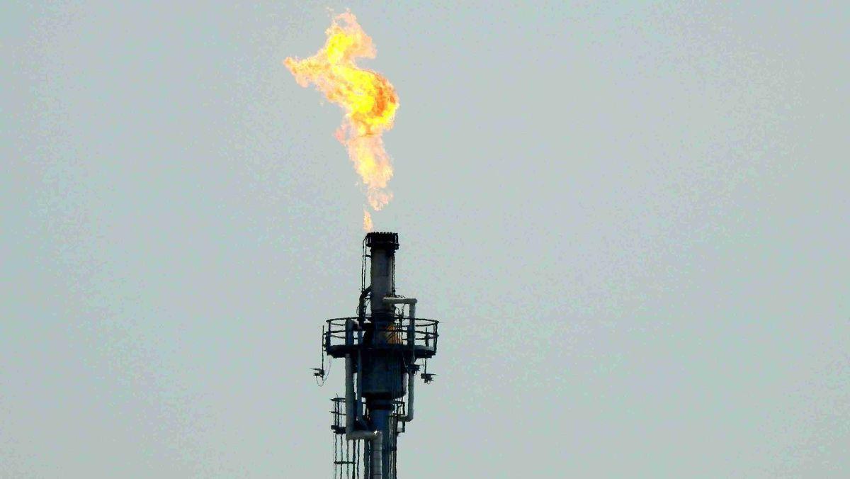 A towering oil rig engulfed in flames against the backdrop of the sky