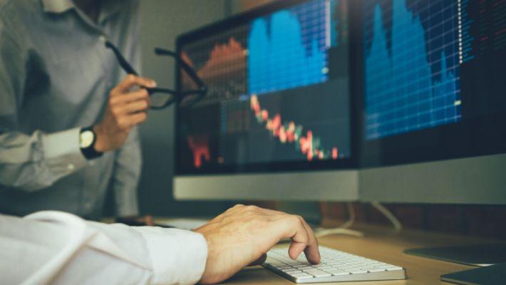 Man at the desk looking at a computer screen showing stock market trading data.jpg