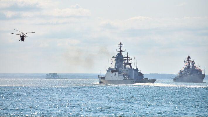 Two naval vessels and a helicopter over the ocean
